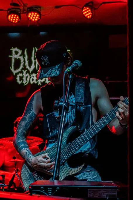 Burnt Chapter’s guitarist playing in front of the band’s banner