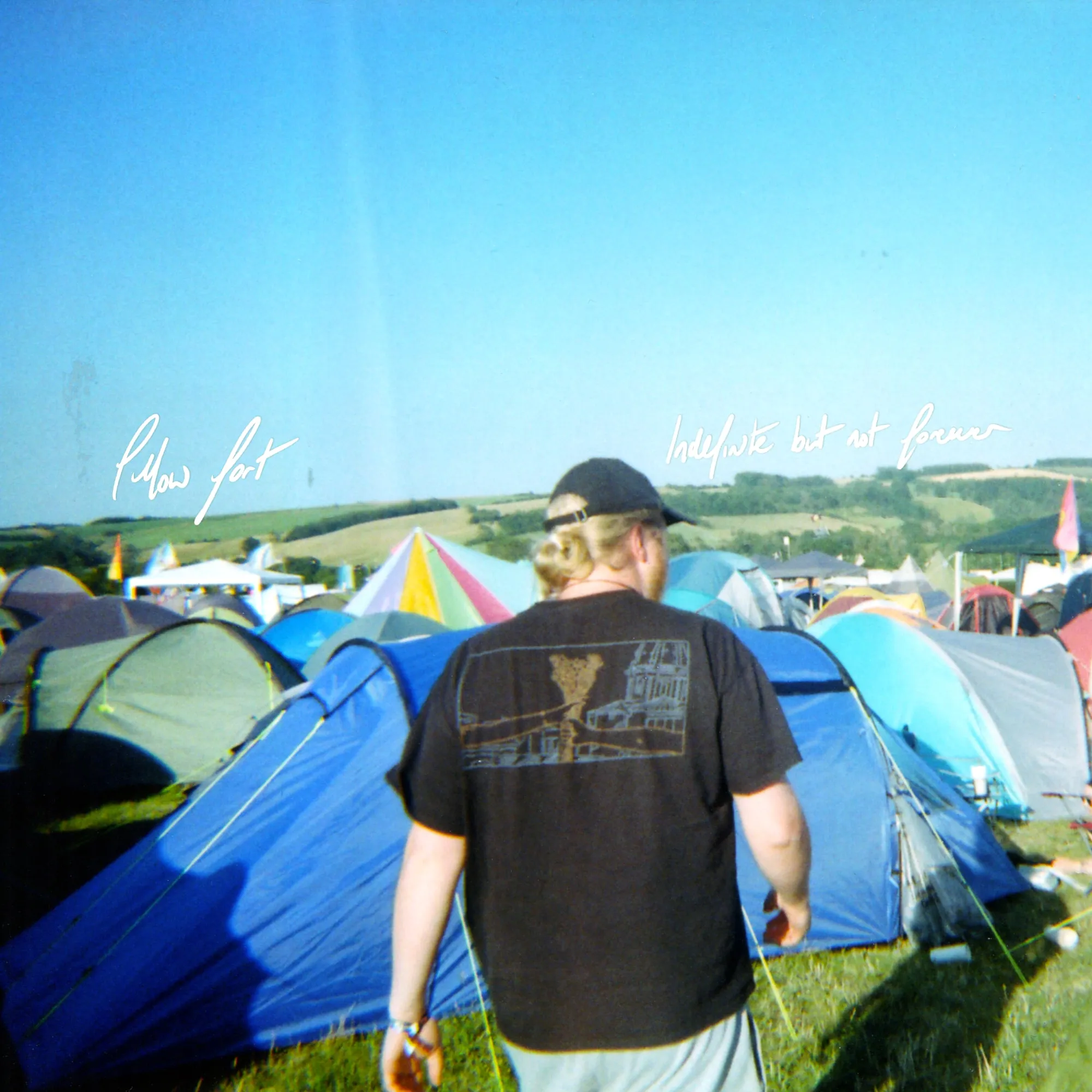 Album artwork for Indefinite, But Not Forever: a person in a cap walking through a sunny festival campsite full of tents
