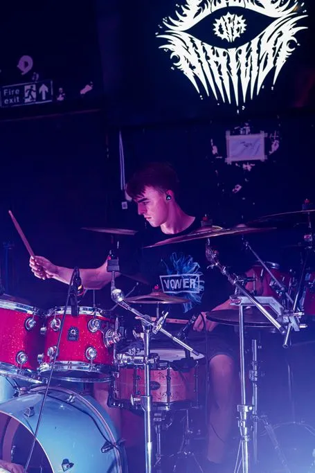 Eye of a Nihilist’s drummer behind the kit, under the band’s glowing logo